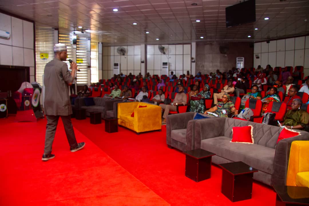 A facilitator addressing participants in a university auditorium
